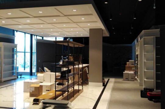 Interior of a store under setup with shelves, boxes, and packing materials near a large window.